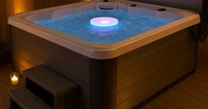 Hot tub upgraded with floating LED light, steps, and cover lifter under ambient lighting